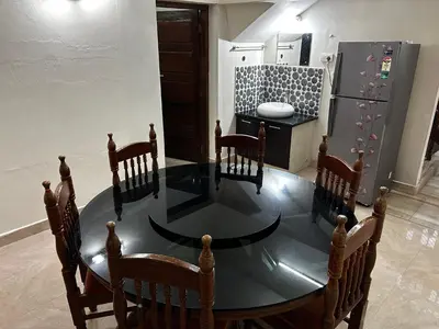 a dining room table with chairs and a refrigerator at Metro Bliz in Alwaye