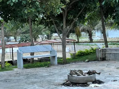 a bench sitting on the beach next to a fire at Rivora Retreat in Nanjangūd