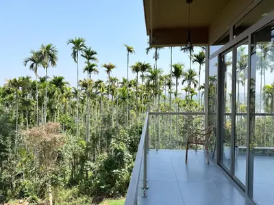 a chair on the balcony of a house with palm trees at Valensa lake view in Kalpetta