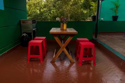 a table with four red stools in a green room at Wayanad home stay in Vythiri