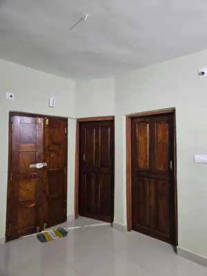 two wooden doors in a room with a white wall at Falcon by wayanora in Padinjarathara