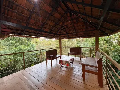 a porch with benches and a table on a deck at Falcon by wayanora in Padinjarathara
