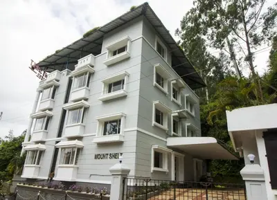 a white building with a black roof at Mounts shelts in Munnar