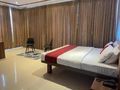 a bedroom with a bed and chairs and curtains at Hemara suites