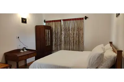 a bedroom with a bed and a table and a window at Brooklyn Villa in Ooty