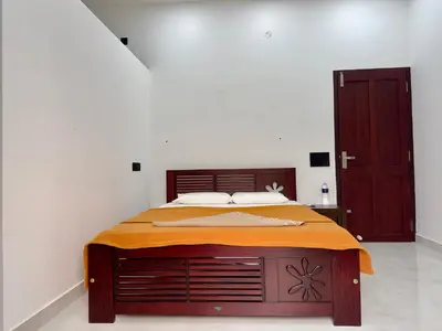a bedroom with a bed with an orange blanket on it at Nana's Residency, Cochin in Alwaye