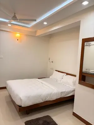 a bedroom with a white bed with a ceiling at Isha suites in Mysore