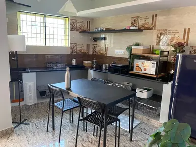 a kitchen with a black table and chairs in it at Mindful Rooftop Yoga Stay in Gokulam Bright, Airy Private Family Terrace Apartment in Mysore