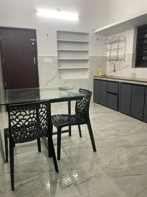 a kitchen with a glass table and two chairs at Mountholidays in Meppādi