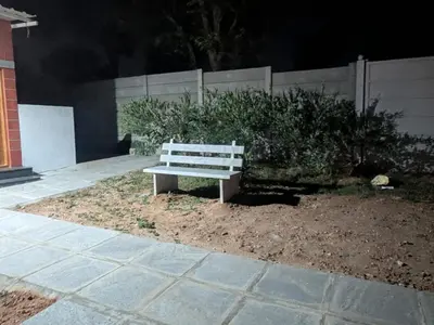 a white bench sitting on the side of a sidewalk at JRD House in Mysore