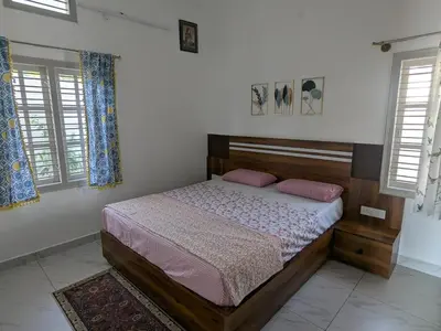 a bedroom with a bed and two windows at JRD House in Mysore