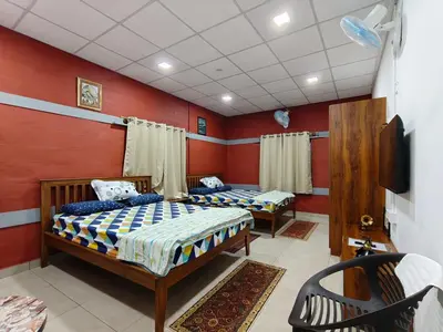 two beds in a room with red walls at JRD House in Mysore