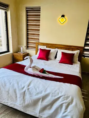 a bedroom with a large white bed with red pillows at Ronz Vista Mount Villa in Padinjarathara