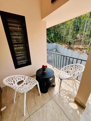 two white chairs and a table on a balcony at Ronz Vista Mount Villa in Padinjarathara
