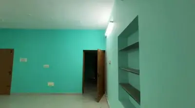 an empty room with a blue wall and shelves at Sindhu Residency in Coimbatore