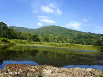 a view of a lake with a mountain in the background at Mathew's Haven, Wayanad - By Arattukulam Hospitality in Thirunelli
