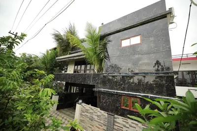 a house with a black facade with a palm tree at Ashiyana Homes in Nedumbassery