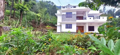 a white house in the middle of a field at Surya Homestay in Marayoor