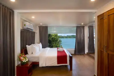 a bedroom with a bed and a large window at Akanta Cherai Beach Resort in Cochin