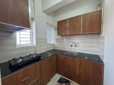 a kitchen with wooden cabinets and a sink at Thirteen in Guruvāyūr