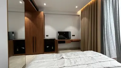 a bedroom with a bed and a cabinet and a television at Cloud Nine Hotel - Kuthuparamba in Kuthuparamba