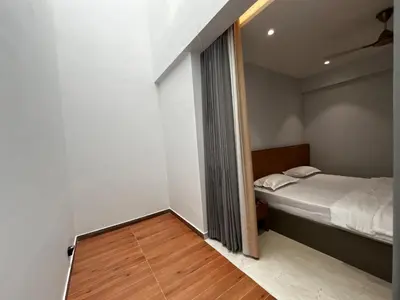 a small bedroom with a bed and a wooden floor at Cloud Nine Hotel - Kuthuparamba in Kuthuparamba