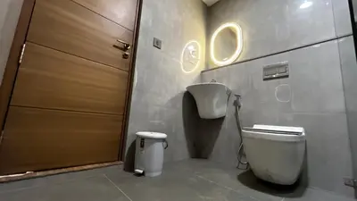 a bathroom with a toilet and a wooden door at Cloud Nine Hotel - Kuthuparamba in Kuthuparamba