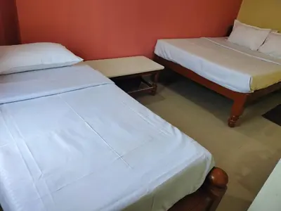 two beds and a bench in a room at ISIRI Rooms in Mysore