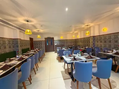 a dining room with tables and blue chairs at Hotel Grand Residency in Mannārakkāt