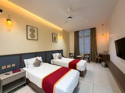 a hotel room with two beds and a television at Hotel Grand Residency in Mannārakkāt