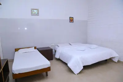 two beds in a room with white walls at Celestial Resorts in Kotagiri