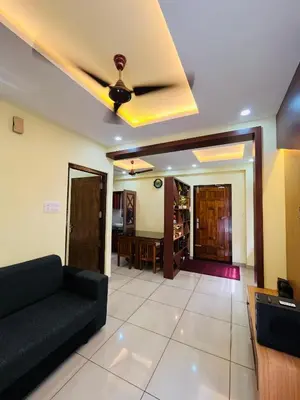 a living room with a couch and a ceiling fan at Panakkal Tower in Guruvāyūr
