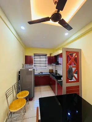 a kitchen with a dining table and a ceiling fan at panakkal tower in Guruvāyūr