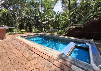 a swimming pool in a yard with a staircase at Kuruva Heritage Home in Wayanad