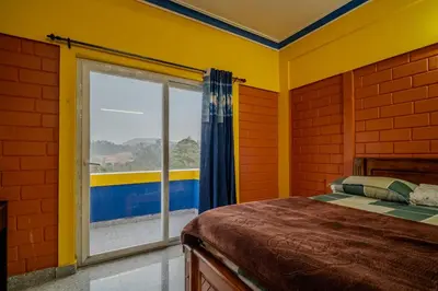 a bedroom with a bed and a large window at The Blue Hist in Naduvattam