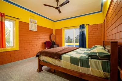 a yellow bedroom with a bed and a ceiling fan at The Blue Hist in Naduvattam