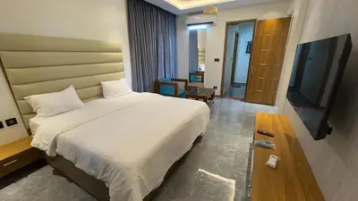 a bedroom with a large white bed and a television at Kurunchi malar Resorts in Hosūr