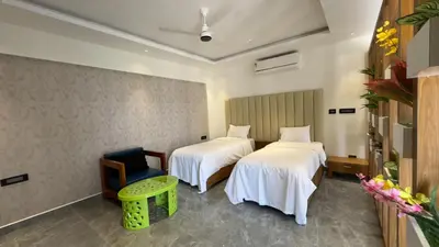 a hotel room with two beds and a chair at Kurunchi malar Resorts in Hosūr