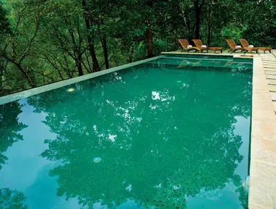 a swimming pool with chairs in the middle of it at Rainforest Resort in Athirappilly