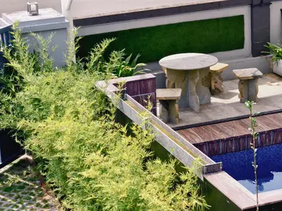 a garden with a wooden table and a bench at Ambadis Beach View 3BHK Pool Villa in Pallipuram