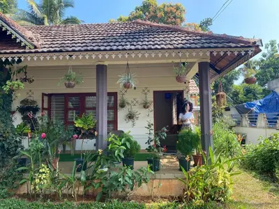 a woman standing on the porch of a house at Merchants Tranquility Home in Vythiri