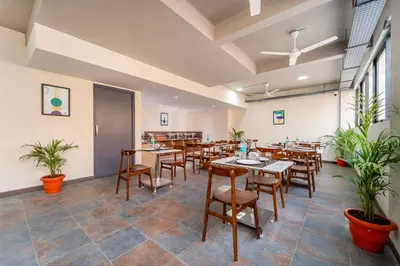 a dining room with tables and chairs and plants at Treebo Premium Cachet Suites in Coimbatore