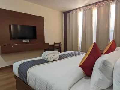 a bedroom with two beds and a flat screen tv at Oxyrich Business Class Hotel in Madikeri