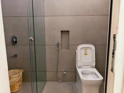 a bathroom with a toilet and a glass shower stall at Ambadis private pool villa in Pallipuram