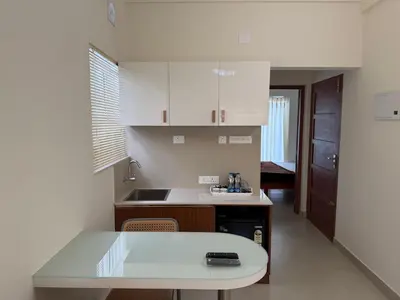 a kitchen with white cabinets and a counter top at Balcony inn in Nedumbassery