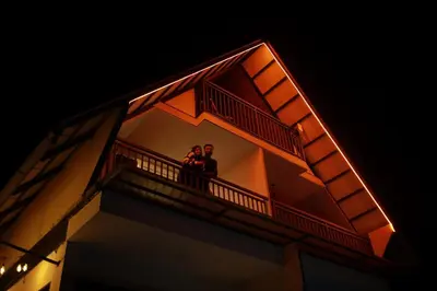 two people standing on a balcony of a building at Mountain View A frame Pool Villa in Meppādi