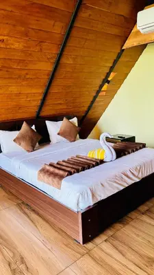 a large bed in a room with a wooden ceiling at Mountain View A frame Pool Villa in Meppādi