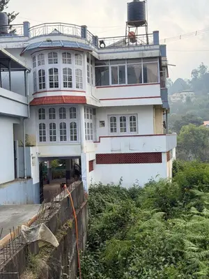 a large white house on top of a hill at DM&sons guesthouse in Coonoor
