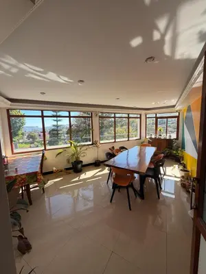 a dining room with a table and chairs and windows at DM&sons guesthouse in Coonoor