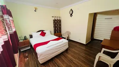 a bedroom with a bed and a table and a desk at Bull Bull Homestay in Ooty